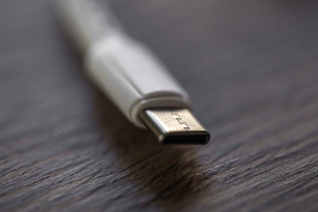 Close-up de conector USB-C metálico sobre superfície de madeira, destacando o padrão moderno de carregamento e dados.
