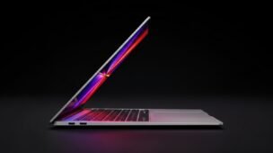 Notebook ultrafino com design premium visto de perfil, parcialmente aberto, com iluminação em degradê rosa e roxo sobre fundo preto, representando tecnologia moderna e alto desempenho.